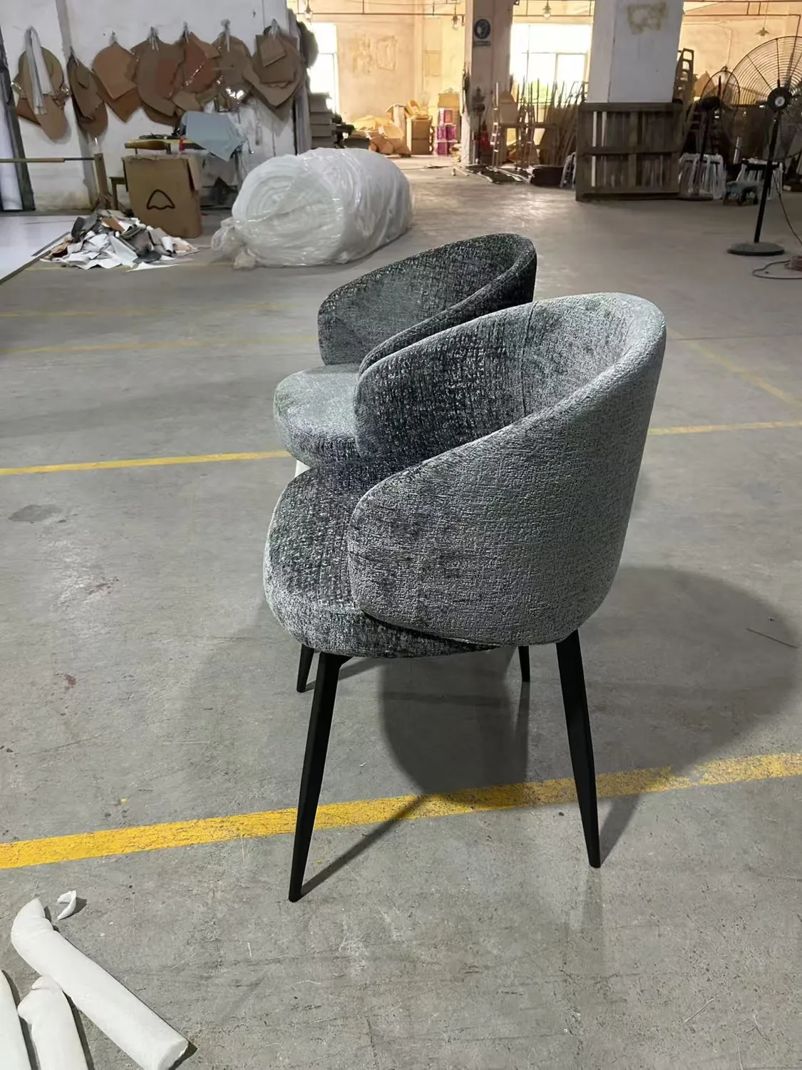 Back and black legs of a grey upholstered dining chair sample in the workshop