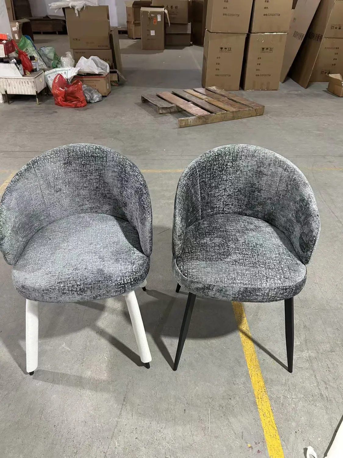 Two grey upholstered dining chair samples photographed from the front in the workshop