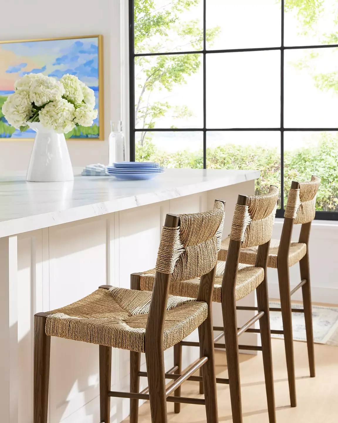 Woven stool beside a bright kitchen island — illustrative lifestyle scene