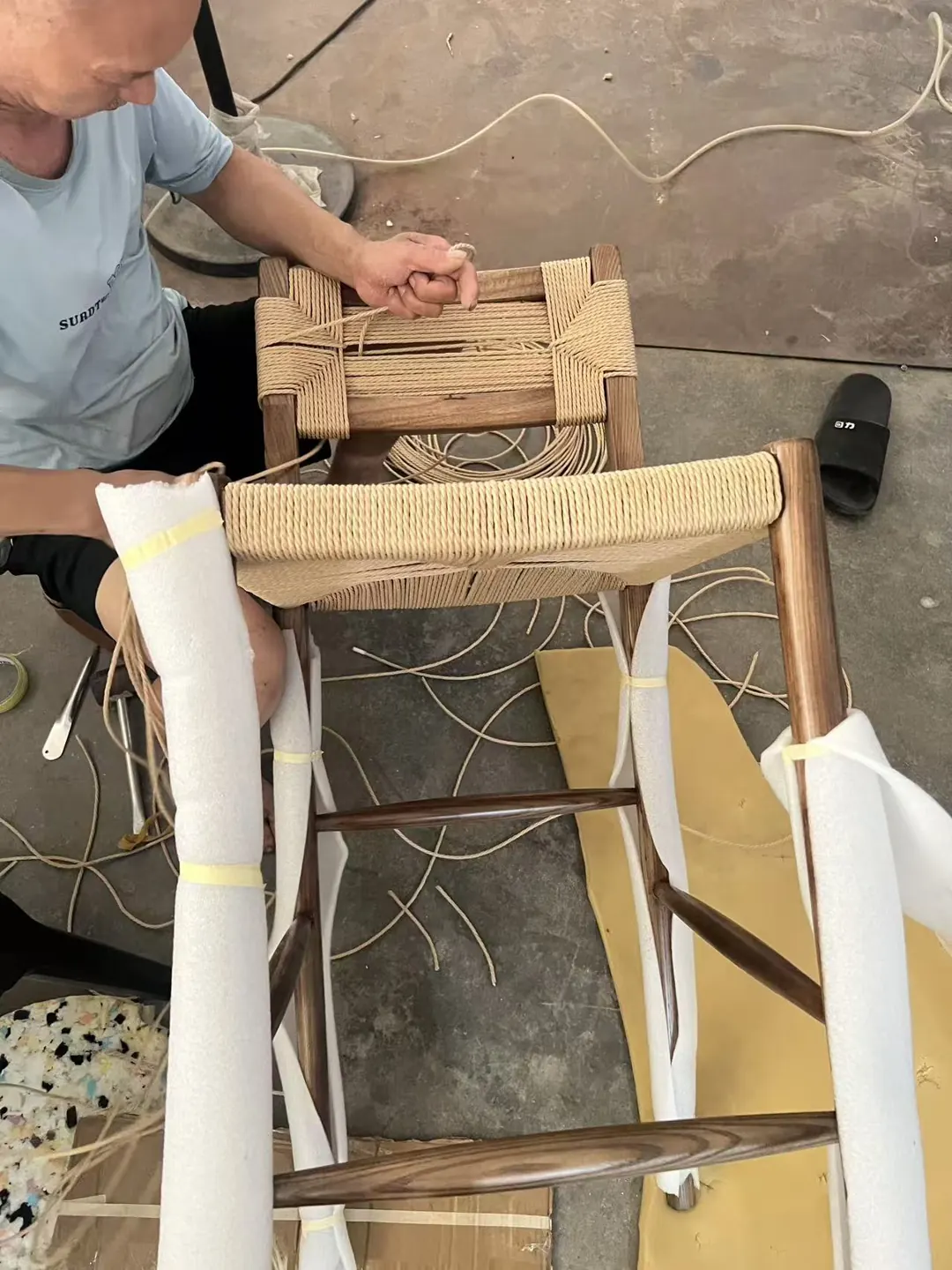 Craftsman hand-weaving the cord seat of the Oslo stool