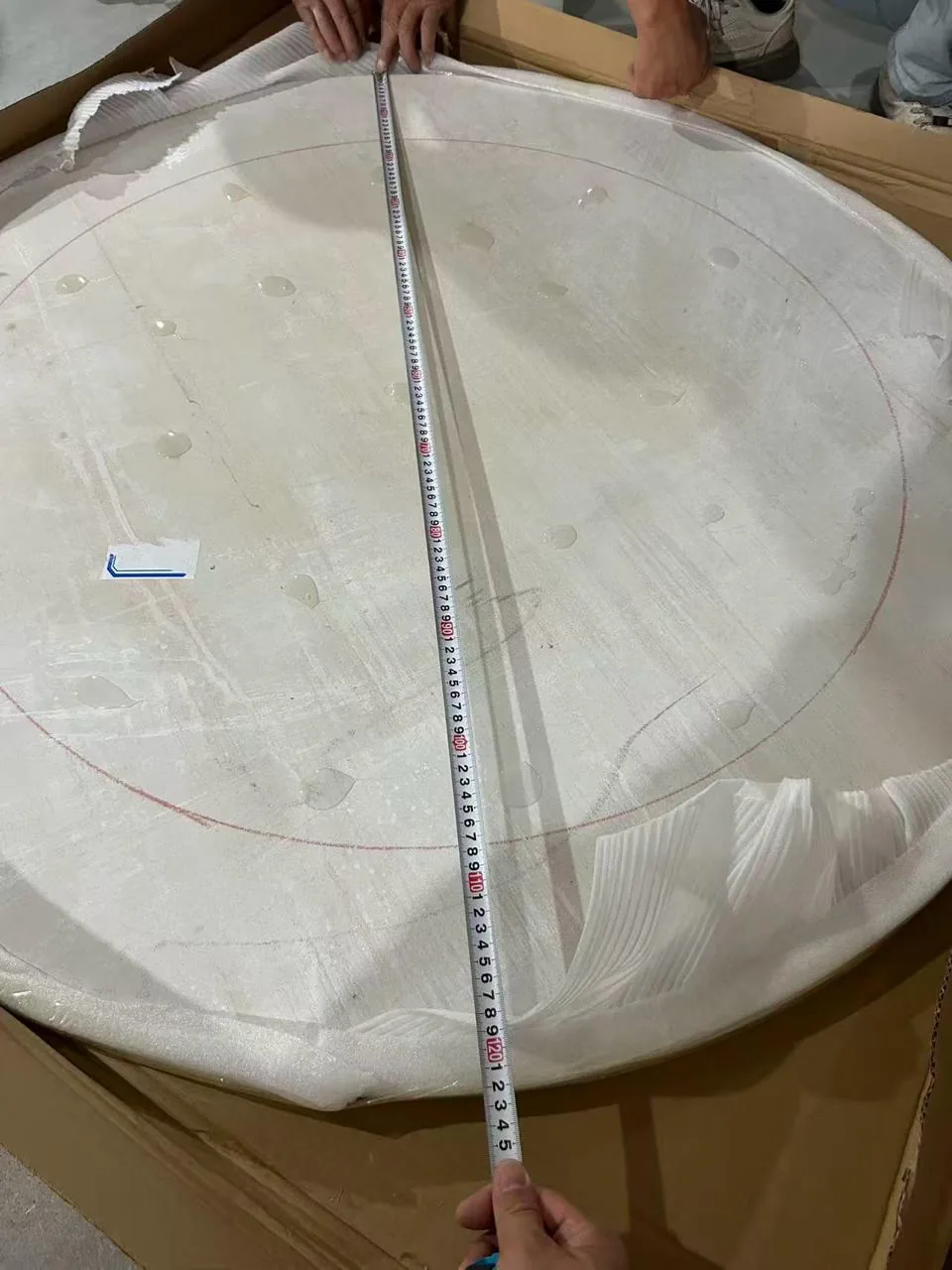 Measuring a protected large round tabletop before packing