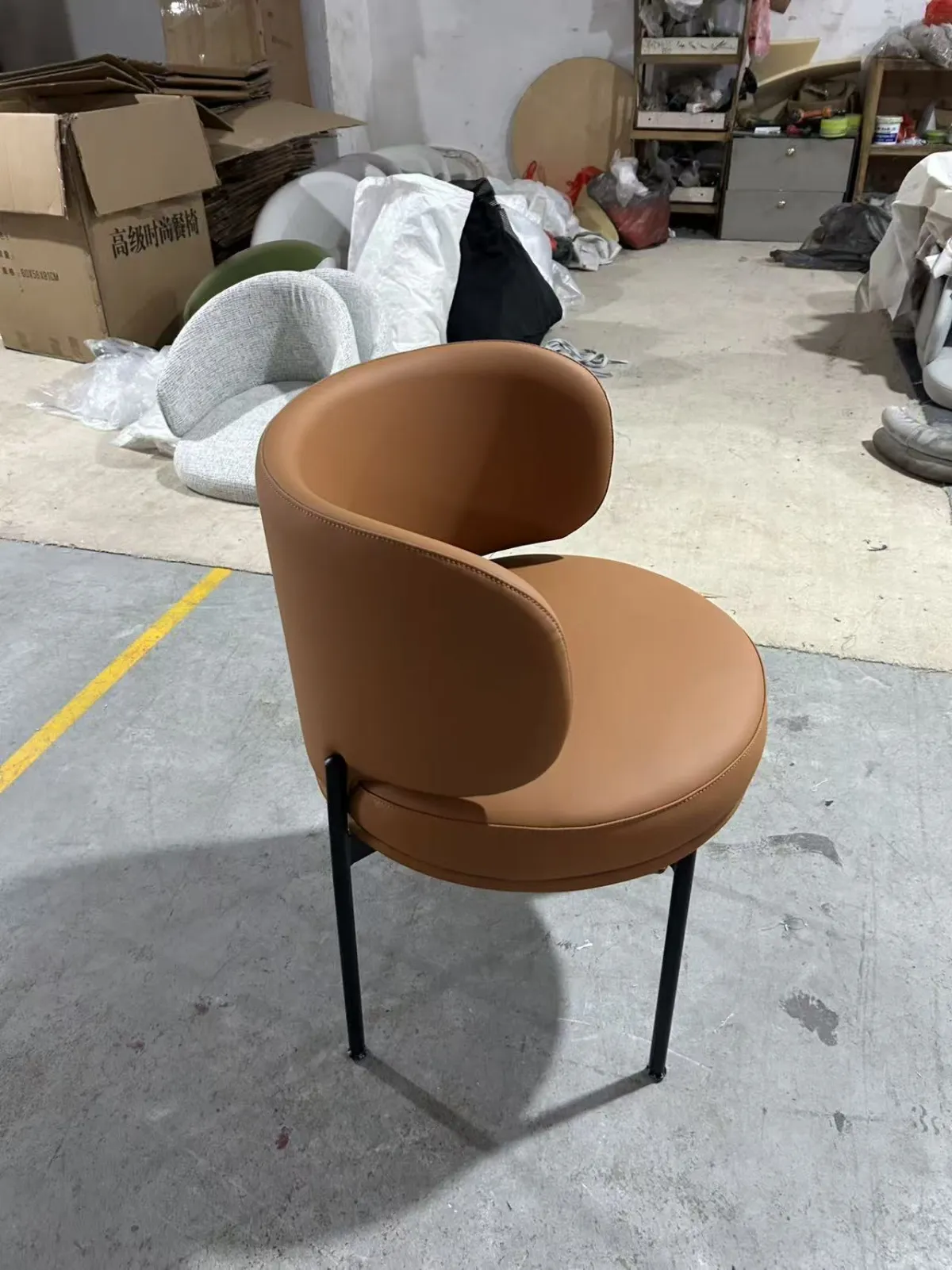 Model 22205 dining chair in the client’s orange-brown microfiber leather with a matte black steel frame, in the workshop