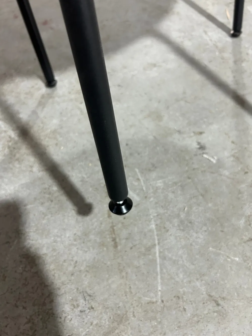 Close-up of a matte black steel leg with a floor glide